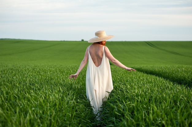 Vrouw in lange witte jurk op een groen veld