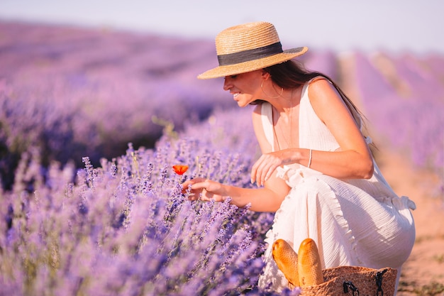 Vrouw in lavendel bloemen veld bij zonsondergang in witte jurk en hoed