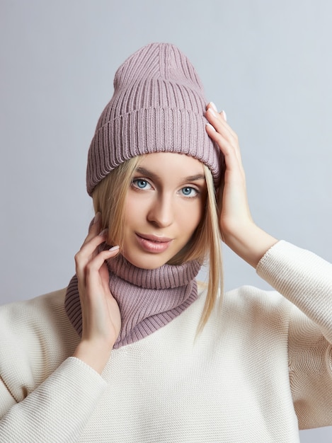 Foto vrouw in lentekleren, sjaal, muts en handschoenen. het meisje is blond met blauwe ogen. warme kleding voor koud lenteweer