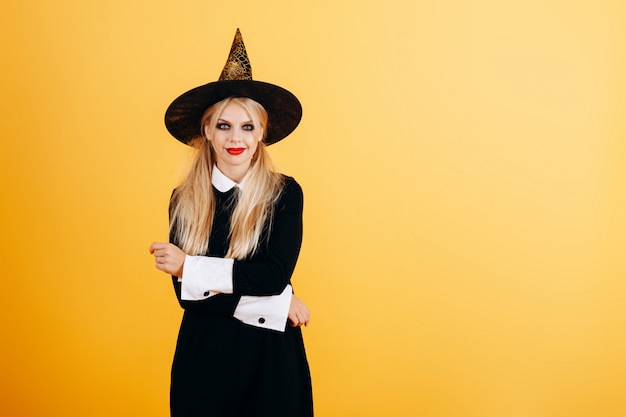 Vrouw in maskeradekleding en hoed het stellen tegen geel.