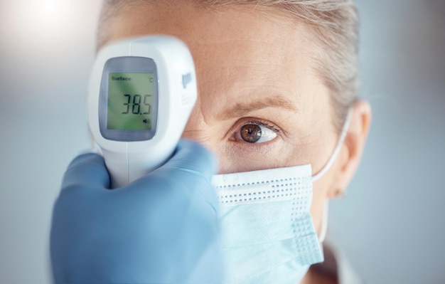 Vrouw in maskerhand van arts en digitale thermometer in ziekenhuis voor covid-veiligheid en gezondheidszorgoverleg Temperatuurtest corona en patiënt in kliniek met medische professional voor examen