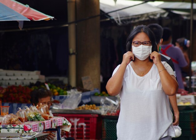 Vrouw in maskers voor bescherming tegen virussen en griep op drukke marktstraten