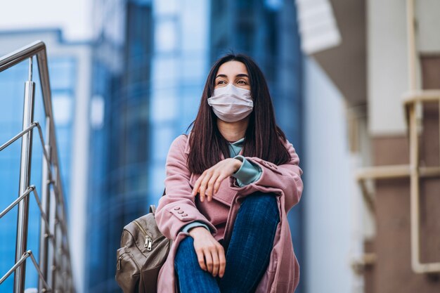 Vrouw in medische masker buiten in de lege stad. Bescherming van de gezondheid en preventie van virusuitbraak, coronavirus, COVID-19, epidemie, pandemie, infectieziekten, quarantaineconcept.