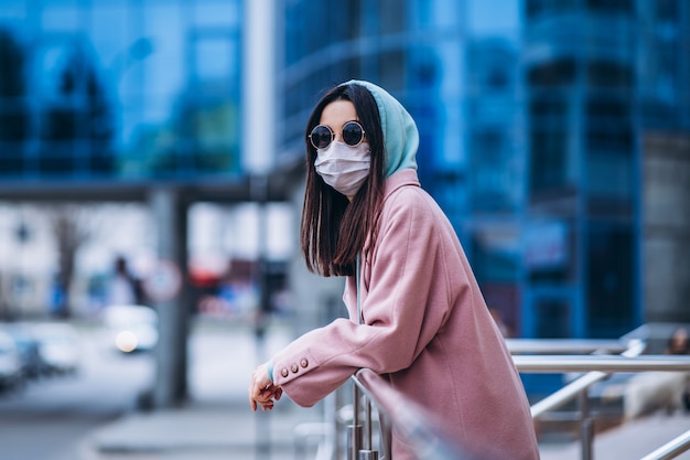 Vrouw in medische masker buiten in de lege stad. Bescherming van de gezondheid en preventie van virusuitbraak, coronavirus, COVID-19, epidemie, pandemie, infectieziekten, quarantaineconcept.