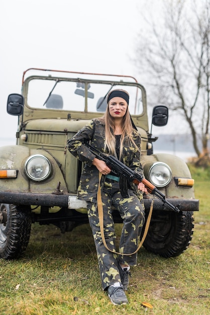 Vrouw in militair uniform met geweer en auto