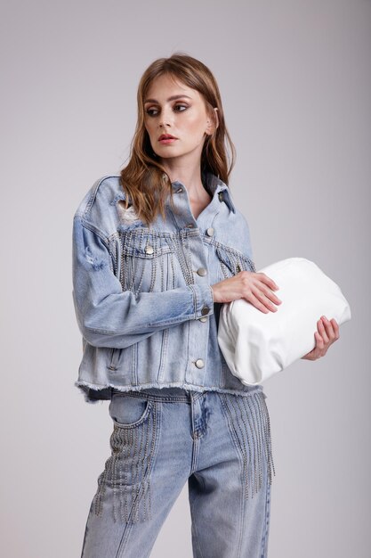 Vrouw in mooie denim jeans oversized jas met strass broek handtas op witte achtergrond