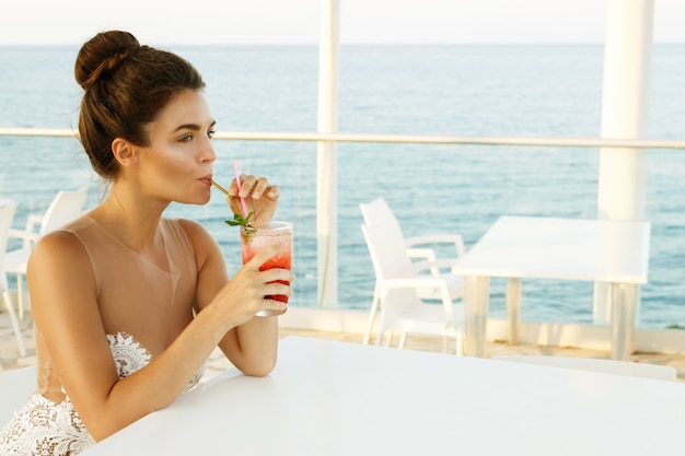 Vrouw in mooie jurk met glas cocktail