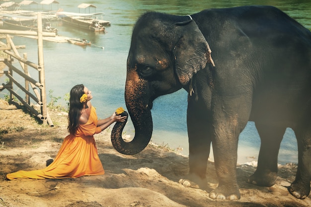 Vrouw in mooie oranje jurk en olifant
