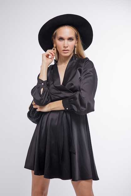 Vrouw in mooie zwarte jurk hoed hoge hakken tas Witte achtergrond Studio Shot portret Blonde