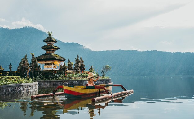 Vrouw in outrigger bij pura ulu danau tempel tegen de hemel