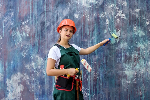 Vrouw in overall en helm schilderen muur met roller