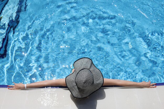 Vrouw in panama liggend op de rand van het bovenaanzicht van het zwembad