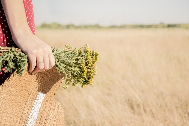 vrouw in polka-dot jurk met boer hoed en boeket bloemen in haar hand, retro stijl vervaagde kleuren