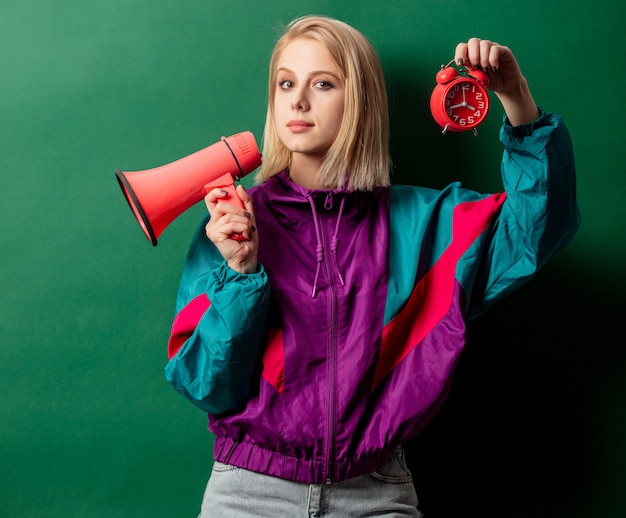 Vrouw in punkjas in jaren 90-stijl met luidspreker en wekker