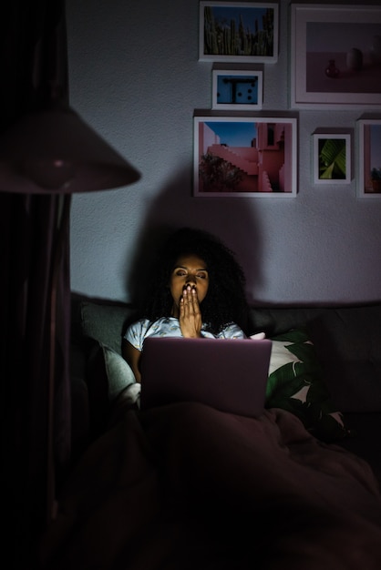 Foto vrouw in pyjama met een computer geeuwen