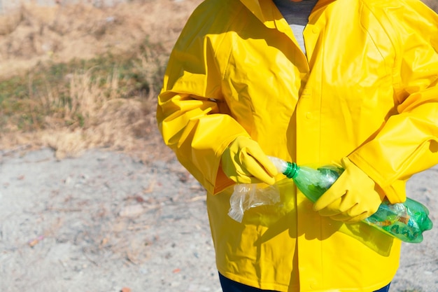 Vrouw in regenjas die plastic huisvuil in park verzamelt