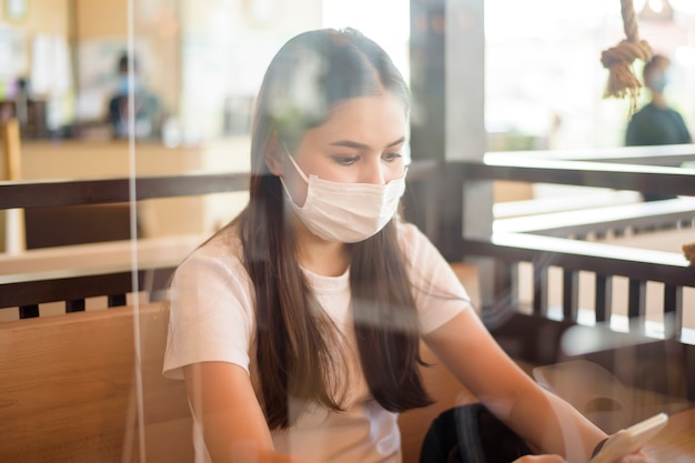 Vrouw in Restaurant met sociale afstands protocol en masker op haar gezicht