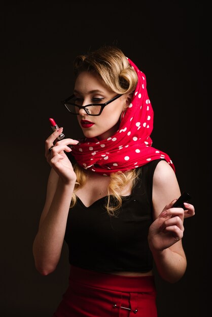 Vrouw in retro stijl poseren met een rode lippenstift op de zwarte achtergrond. Pinup portret