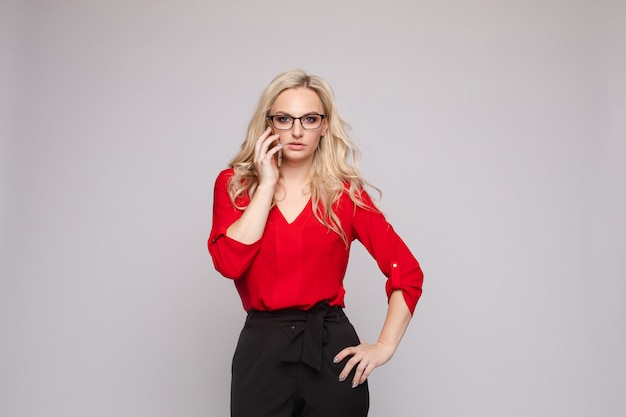 Vrouw in rode blouse en rok die telefoon houden