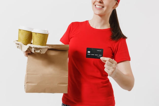 Vrouw in rode dop, t-shirt geven fastfood bestelling geïsoleerd op een witte achtergrond. Vrouwelijke koerier met creditcard, papieren pakje met eten, koffie. Levering van producten van winkel of restaurant aan huis.