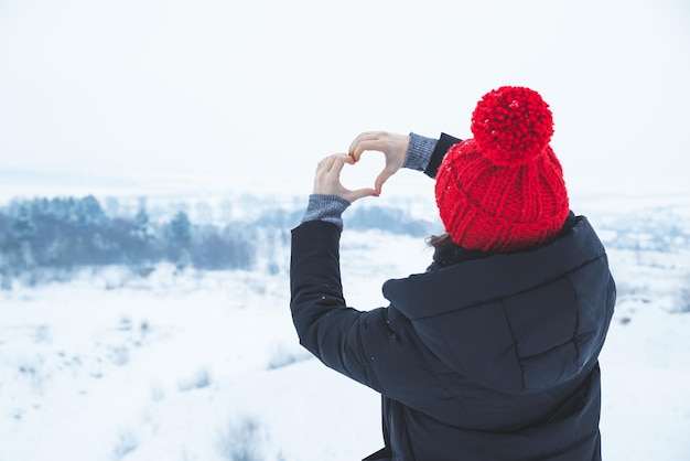 Vrouw in rode hoed maakt liefdessymbool met haar handen wintertijd