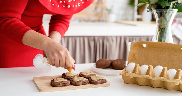 Foto vrouw in rode jurk die valentijnskoekjes maakt in de keuken