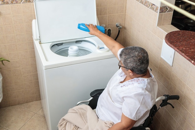 Vrouw in rolstoel kleren wassen in wasmachine