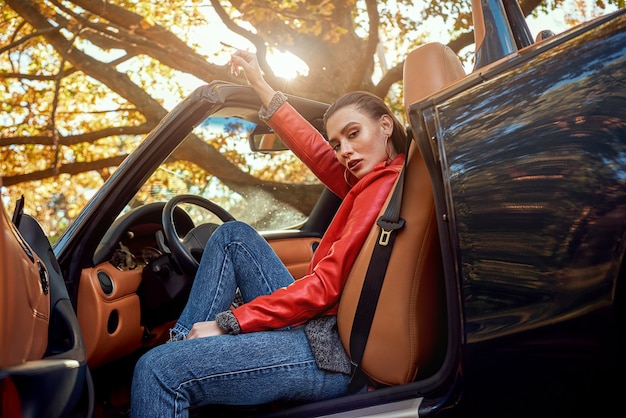 Vrouw in rood in cabriolet ze lacht