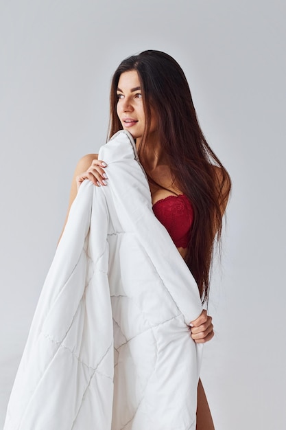 Vrouw in rood ondergoed die haar lichaam behandelen door handdoek in de studio tegen witte achtergrond.