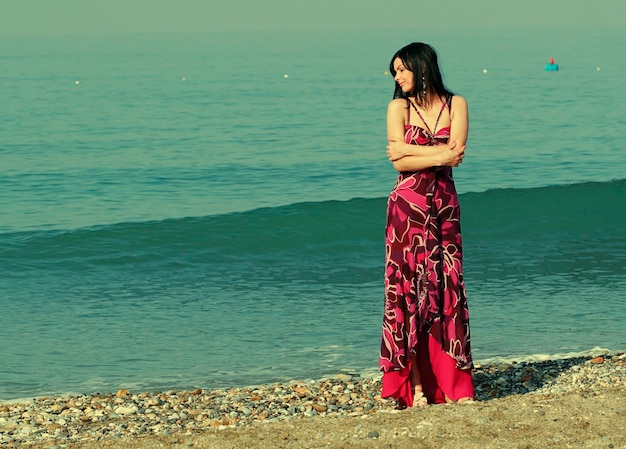 Vrouw in roze jurk op het zeestrand