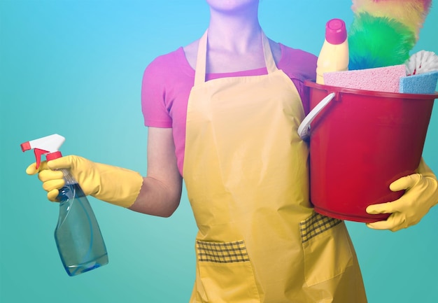 Vrouw in schort met rubberen handschoenen en stofdoek