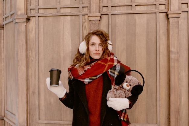 Vrouw in sjaal en bontoorkappen met teddybeer.