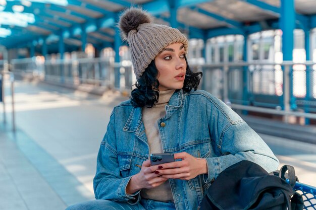 vrouw in spijkerjasje is aan de telefoon en wacht op een trambus bij de halte Lifestyle foto