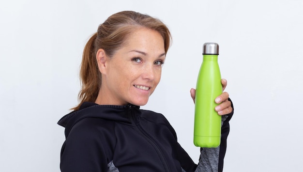 Vrouw in sportieve jurk met groene thermosfles met water