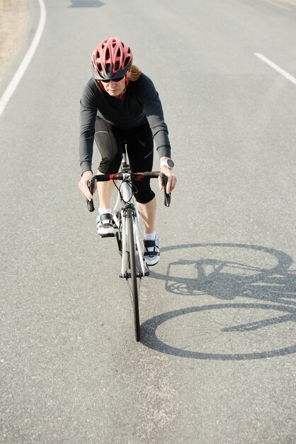 Vrouw in sportkleding die buiten op een fiets rijdt, traint voor triatlon of fietscompetitie