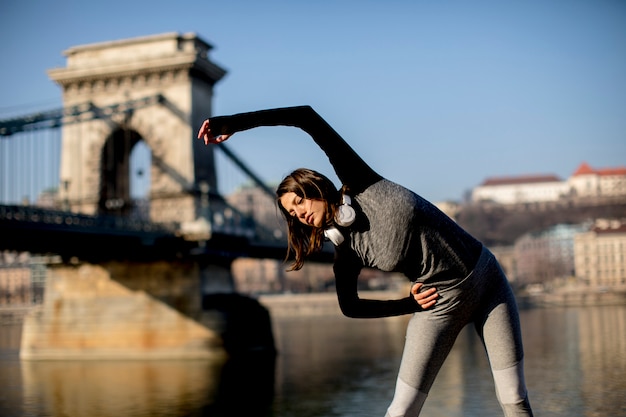 Vrouw in sportkleding die zich uitstrekt over de rivierpromenade van Donau in Boedapest