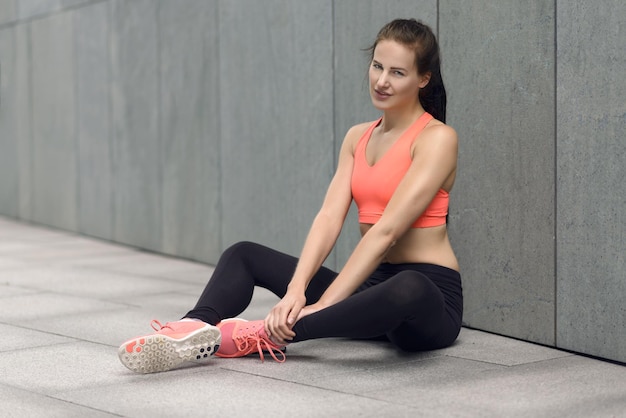 Foto vrouw in sportkleding zit buiten.