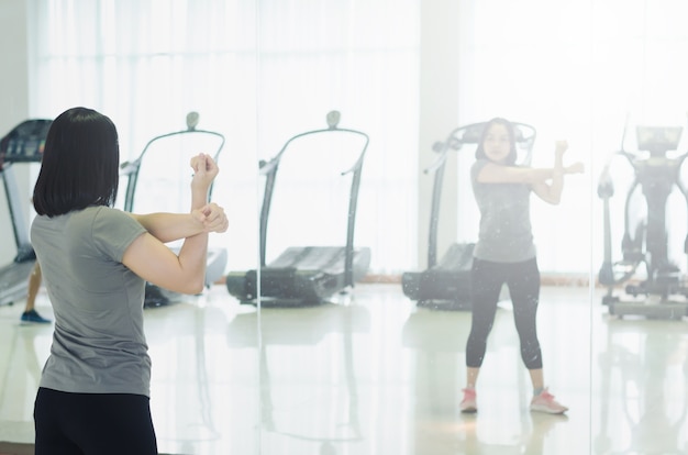 Foto vrouw in sportkleren die haar wapen uitrekken vóór oefening of cardiotraining in gymnastiek