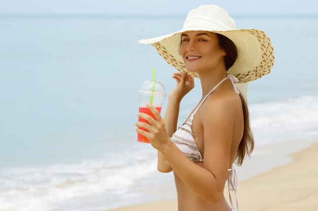 Vrouw in strandhoed met een cocktail