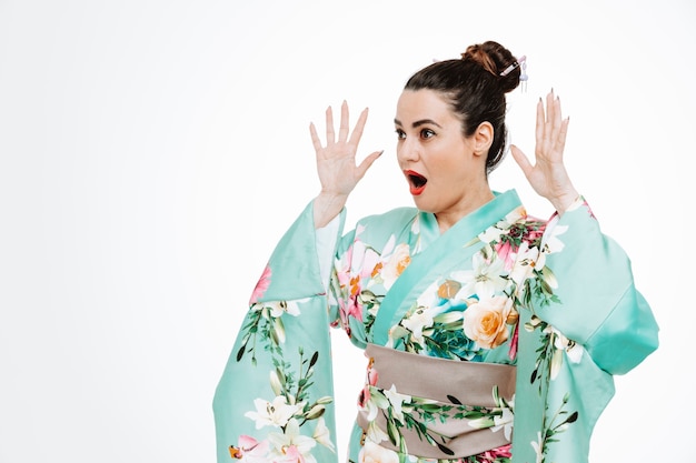 Vrouw in traditionele Japanse kimono kijkt opzij, blij en opgewonden, armen opstekend in verrassingsuitdrukking op wit