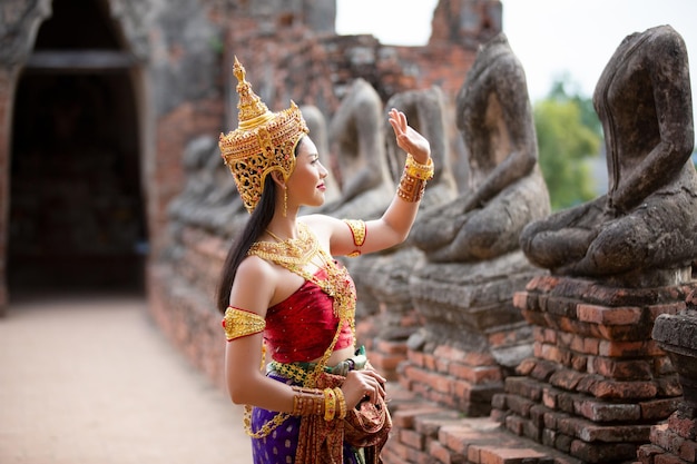 Foto vrouw in traditionele kleding die bij standbeelden bij het tempelgebouw staat