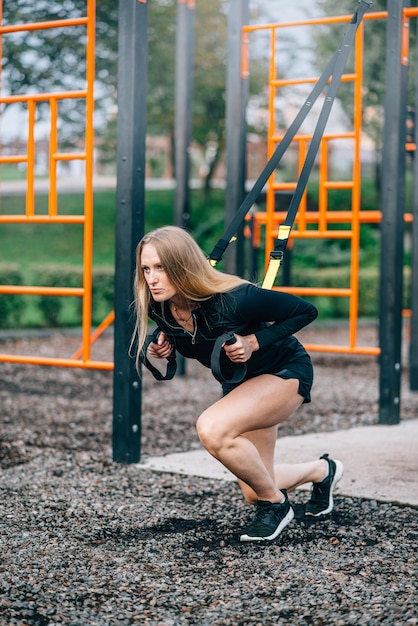 Vrouw in training Jonge atletische vrouw in sportkleding treinen met fitness bandjes op sportveld