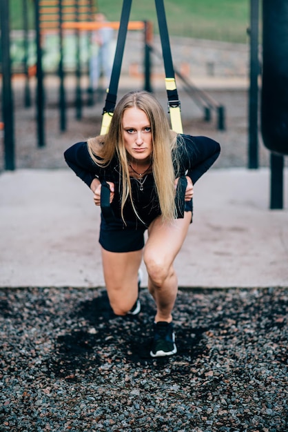 Vrouw in training Jonge atletische vrouw in sportkleding treinen met fitness bandjes op sportveld