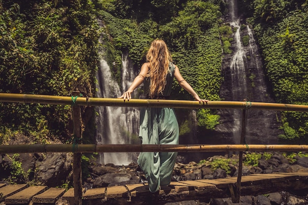 Vrouw in turquoise jurk bij de Sekumpul-watervallen in de jungle op het eiland Bali Indonesië Bali Travel Concept