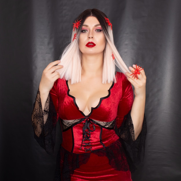 Vrouw in vampierkostuum met veel rode spinnen op haar haar