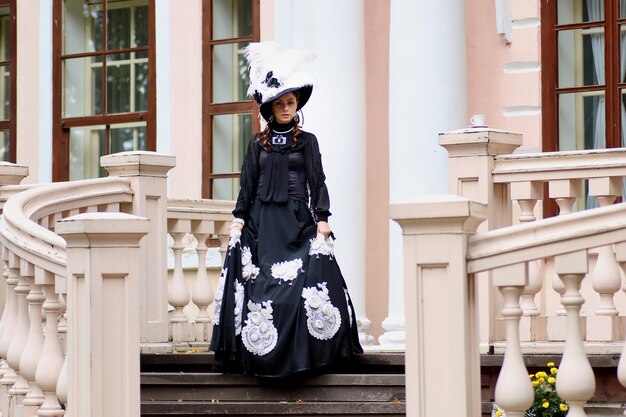 Vrouw in vintage jurk op veranda van kasteel