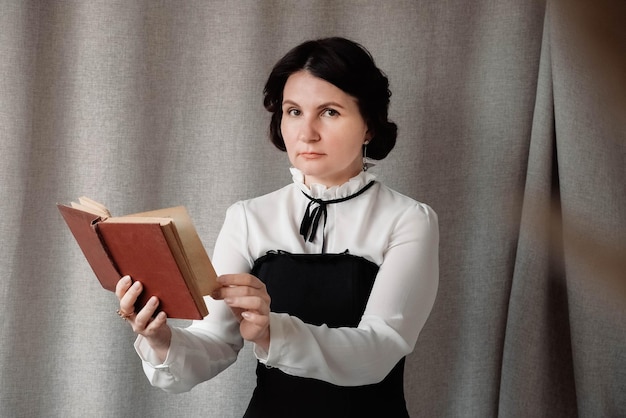 Vrouw in vintage stijl gekleed met een boek in zijn handen op een achtergrond van linnen doek.