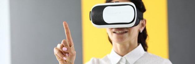 Vrouw in virtual reality-bril staat en houdt haar duimen omhoog. Onderdompeling in de wereld van virtual reality-concept