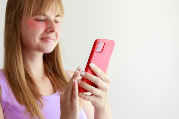 Vrouw in vlekken onder haar ogen met een smartphone op een witte achtergrond