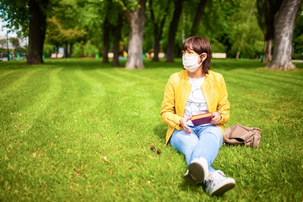 Vrouw in vrijetijdskleding en medische maskerzitting in het park